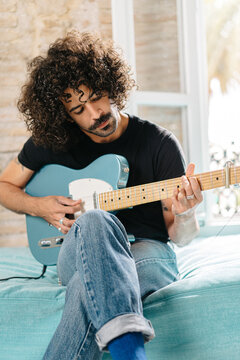 Musician playing electric guitar at home