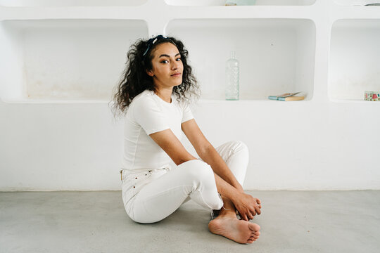 Young woman in casual white clothes sitting on floor
