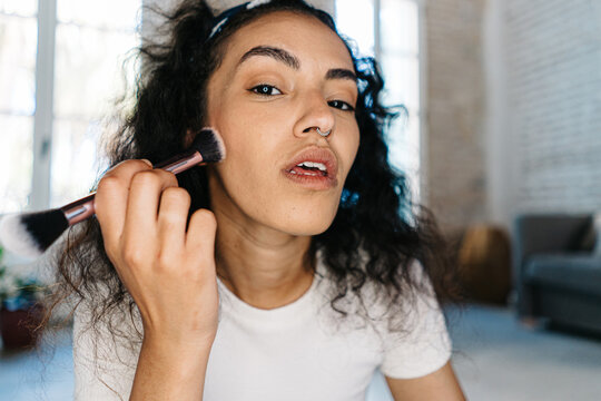 Beauty blogger applying makeup on cheek