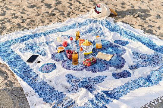 Picnic food and drinks sitting on a beach blanket