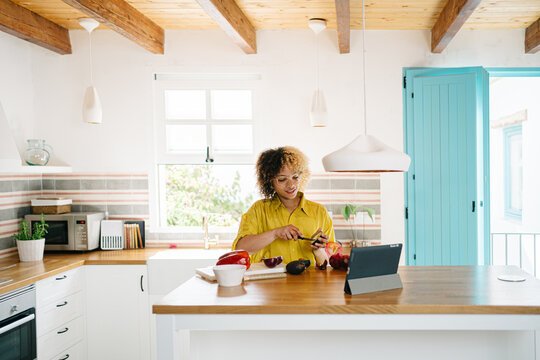 Woman watching video on tablet while cooking in kitchen