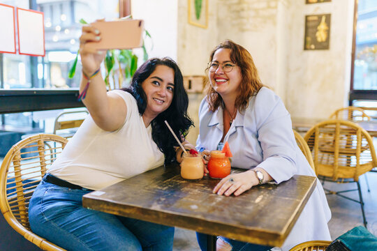 Two plus size girls take a selfie in a bar