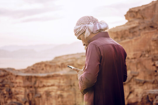 Arabic man using smartphone near mountains