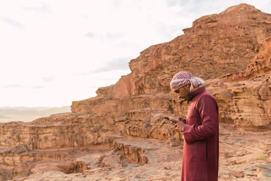 Arabic man using smartphone near mountains