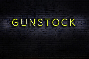 Night view of neon sign on brick wall with inscription gunstock