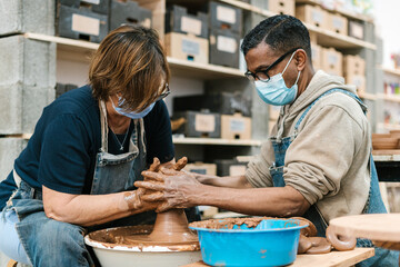 Diverse potters using wheel to create pot