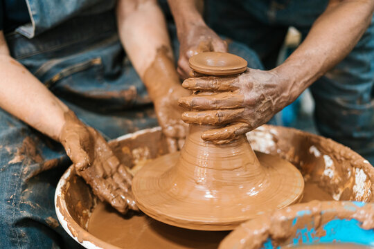 Craftsmen's hands shaping a vase on the lathe