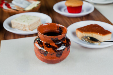 Jarrito or clay cup with café de olla, traditional mexican coffee and some desserts in Mexico