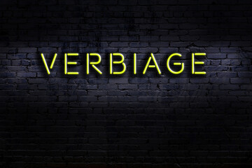 Neon sign. Word verbiage against brick wall. Night view