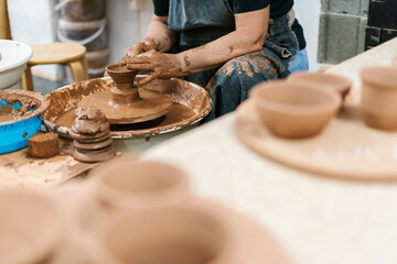 Hands of unrecognizable woman sitting on potter's wheel