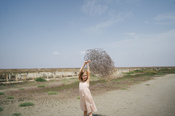 Girl with dry tumbleweed on summer day