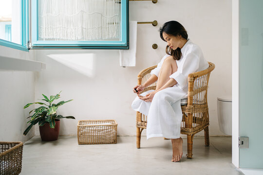 Asian woman doing pedicure at home