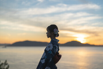 夕暮れの海にいる浴衣の女性