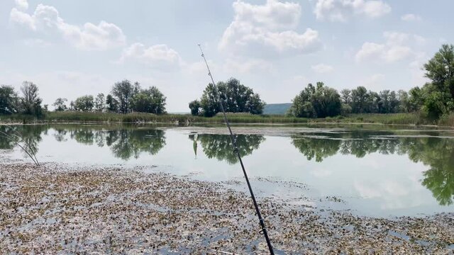 Vobler is swinging at tip of spinning rod or fishing rod against backdrop of lake