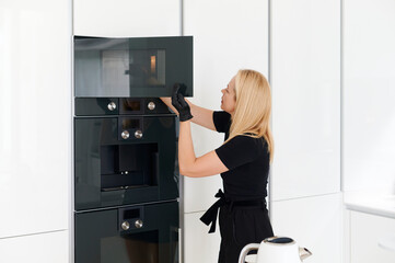 Woman cooking food in her kitchen oven at home