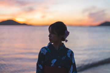 夕暮れの海にいる浴衣の女性