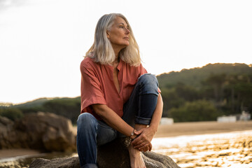 Pensive Beautiful mature woman relaxing at beach