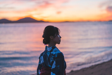 夕暮れの海にいる浴衣の女性