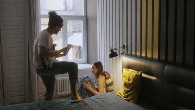  Handsome young man playing guitar to his beautiful girlfriend.