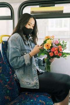 Woman on the Bus with Phone and Flowers