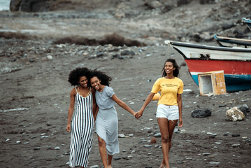 Black three women walking near boat and seashore