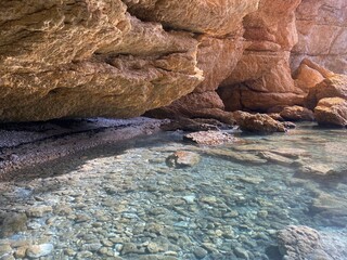 Pebbles beach in beautiful rocks at summer. Turquoise transparent sea water. Paradise lagoon secluded place for relax. Scenic coastal island landscape. Stones and smooth gravel on ocean floor.