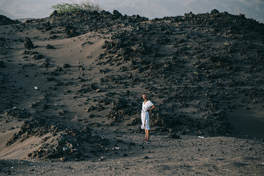 African woman standing on volcanic sand dune on beach