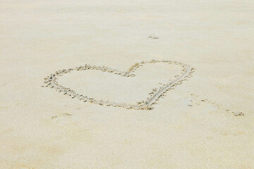 Heart drawn in the sand on Beach background