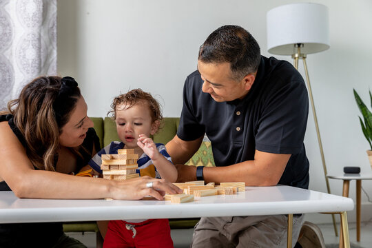 Man and Woman Watch Son Stack Blocks
