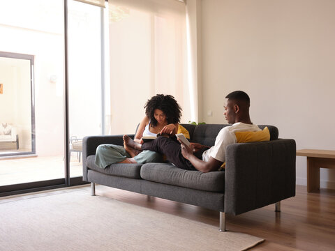 Black couple spending free time on couch.