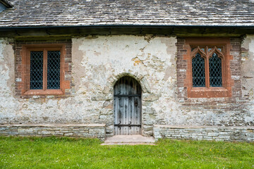 A wooden door and two windows in a historic medieval church. 