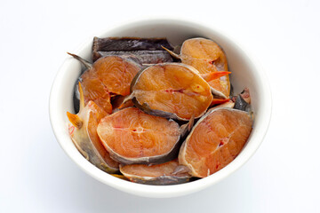 Catfish cut pieces in white bowl on white background.