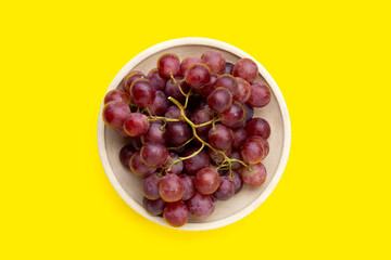 Fresh grape in plate on yellow background.