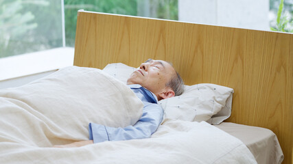 ベッドで寝ているシニア男性