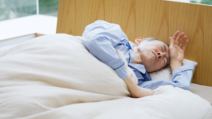 Obraz na płótnie Canvas ベッドで寝ているシニア男性