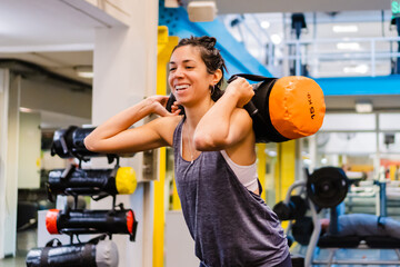 young hispanic latina woman in a gym doing squats with core bag