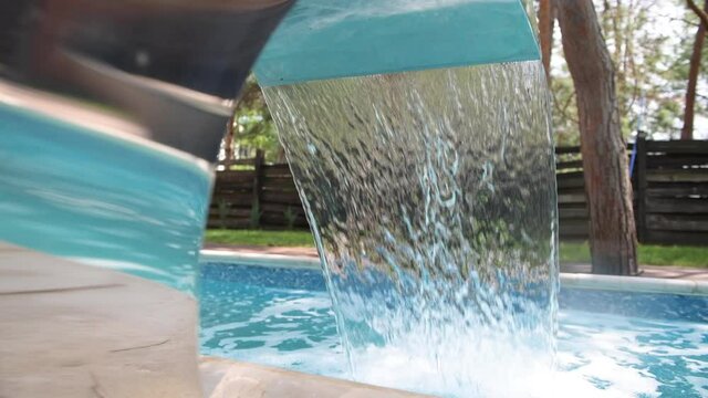 Stainless steel fountain waterfall at modern resort hotel swimmping pool with dynamic clean water stream, spa refreshing technology