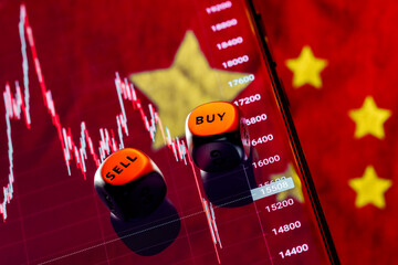 Dices with the words SELL BUY on the edges. On background the chart of the fall of the stock index...