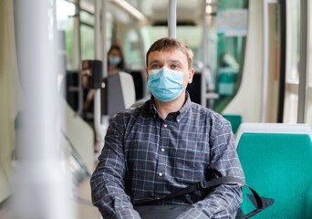Fototapeta na wymiar Man in protective medical mask and gloves rides in public transport
