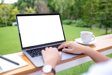 Fototapeta premium Mockup image of a woman using laptop computer with blank white desktop screen while working in the outdoors