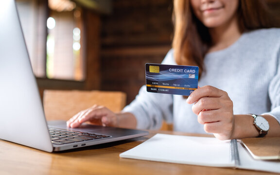 Closeup image of a business woman holding credit cards while using laptop computer for online payment