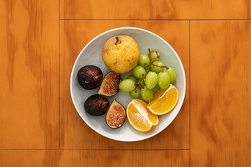 Pear, grapes, orange and fig in a bowl upper shot