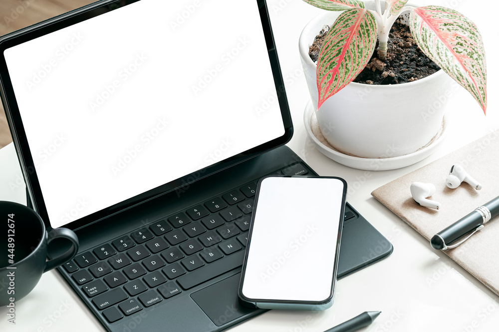 Poster mockup blank screen smartphone and tablet with keyboard on the table.