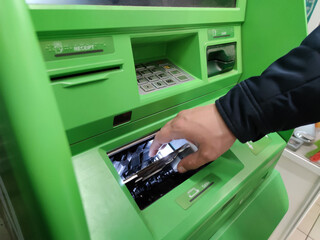 Hand of man with a credit card, using an ATM. Man using an atm machine with his credit card.