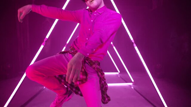 Professional Hip Hop break dancer . Stylish young man dancing with real strobe lights . Against colored background with triangle shape of led lights . Real decoration . Shot on RED EPIC Cinema Camera