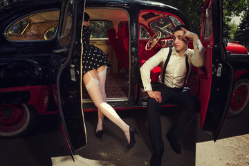 Fototapeta na wymiar Young couple sitting inside retro car