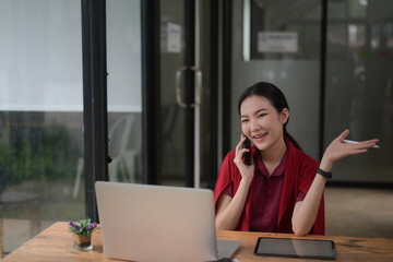 Smiling female talking on mobile phone while sitting in office.