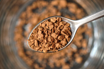 Close up, Freeze Dried Instant Coffee on Tea Spoon with Glass Coffee Cup Background.