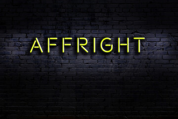Neon sign. Word affright against brick wall. Night view