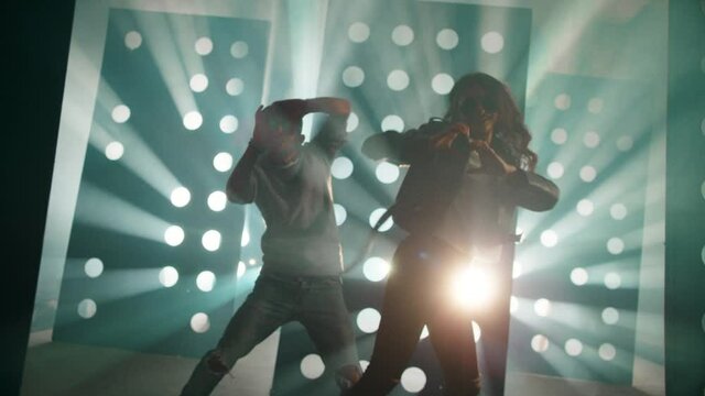 Professional Hip Hop , freestyle or swag dancers . Stylish young couple dancing crazy modern dance near decorative walls with many circle holes and spotlight . Shot on RED HELIUM Cinema Camera .